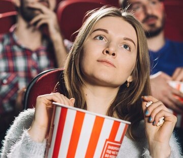 Woman at Cinema eating popcorn and watching a movie