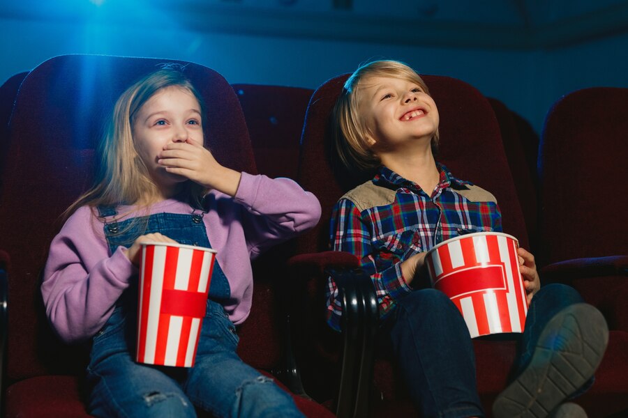 Children sitting in Cinema seats sharing popcorn